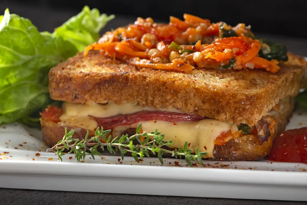 Toasted sandwich with melted cheese and a pile of shredded pickled vegetables on top